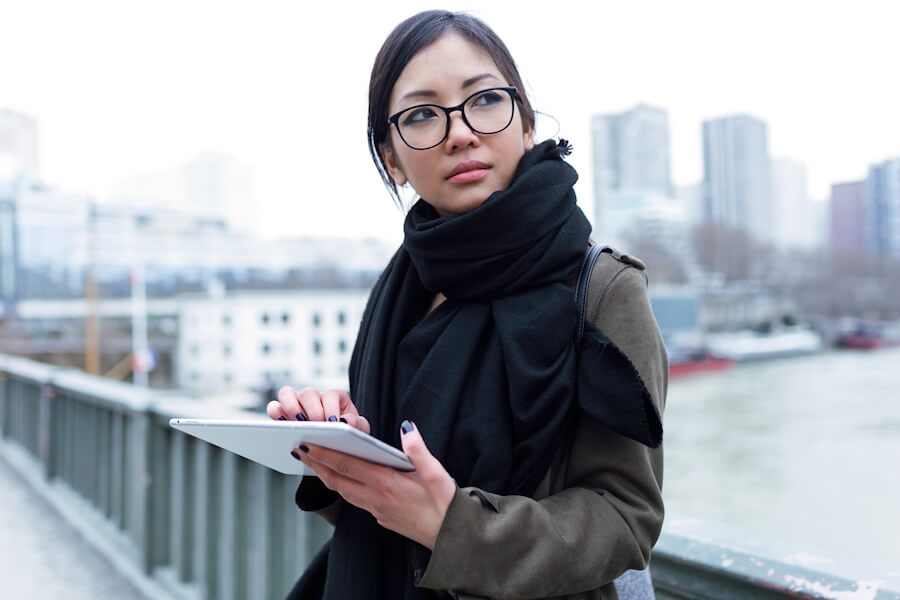 Beautiful Asian Young Woman Using Her Digital Tablet In Front Of Seine River In Paris.